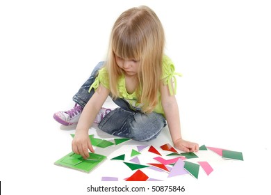 cute girl playing with colorful puzzle over white