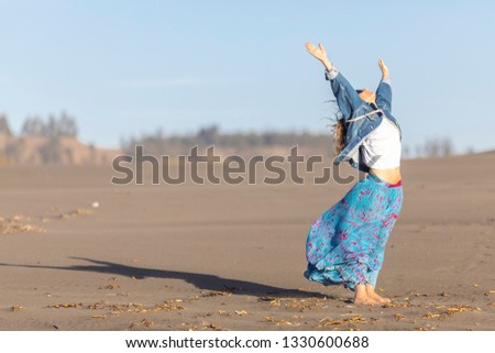 Cute girl portrait with the hands up in the air while the woman is looking to the sky over the sand of a Las Brisas wild beach an amazing an idyllic scenery in the Chilean outdoors, South America
