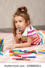 A cute girl in rainbow clothes draws a rainbow with multi-colored markers. House. Childhood. - Shutterstock ID 2208882811