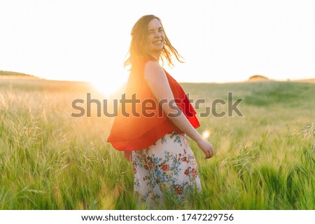 Cute girl in red dress, laughing with joy outdoors in the springtime sunset . 