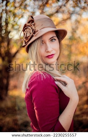 Similar – Portrait of smiling blonde woman with hat while she walks in nature looking into camera.