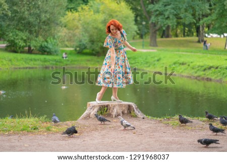 cute girl in retro dress feeds pigeons birds in city Park in summer