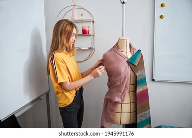 Cute girl seamstress using mannequin in sewing workshop - Powered by Shutterstock