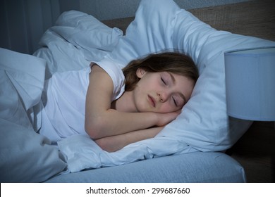 Cute Girl Sleeping On Bed In Dark Bedroom