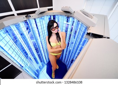 Cute Girl In A Swimsuit In A Special Cabin With UV Lamps For The Treatment Of Psoriasis. Light Therapy, Phototherapy