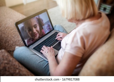 Cute girl talking with her grandmother within video chat on laptop, digital conversation, life in quarantine time, self-isolation - Powered by Shutterstock