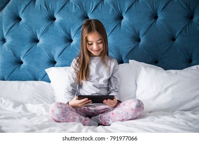 Cute girl using a tablet computer in her bedroom