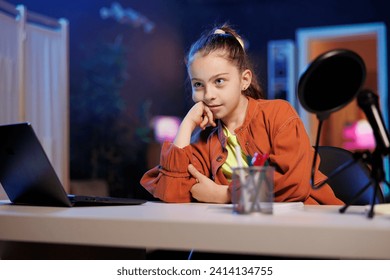 Cute girl utilizes high quality recording gear to shoot introductory segment for vlog channel. Young media star in blue neon studio welcomes devoted fan community, introducing today video subject