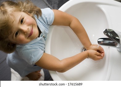 Cute girl washing hands in bathroom