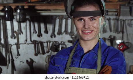 cute girl welder in uniform in the garage in the background of the workbench . Women's work - Powered by Shutterstock