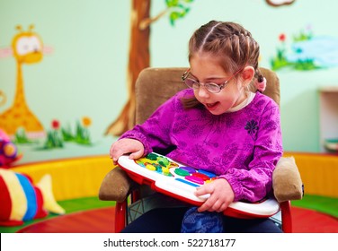 cute girl in wheelchair playing with developing toy in kindergarten for children with special needs