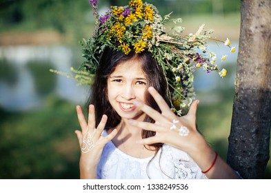 Cute Girl In White National Dress Weaves A Wreath Of Flowers And Grass At The Pagan Festival Of Spring