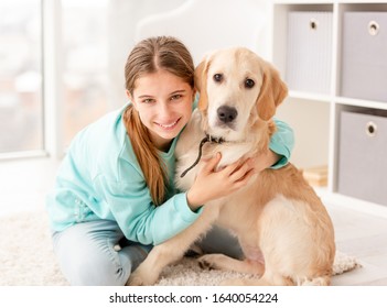 Cute girl with wide smile hugging adorable dog in light room - Shutterstock ID 1640054224