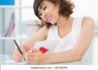 Cute girl writing a love card for her boyfriend