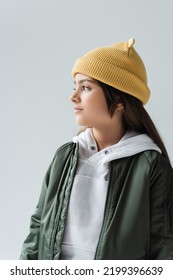 Cute Girl In Yellow Beanie Hat And Bomber Jacket Looking Away Isolated On Grey