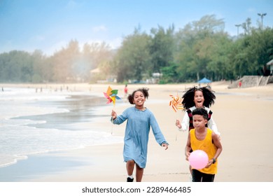 Cute groups of African kids have fun activity together on summer beach blue sea, two girls with black curly hair and boy running on tropical beach, happy childhood friends on holiday vacation. - Powered by Shutterstock