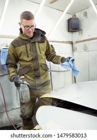 Cute Guy In Black Glasses With Black Gloves Displays The Shape Of The Hood For The Subsequent Painting Of The Car. Guy - A House Painter Working On A Car In The Garage