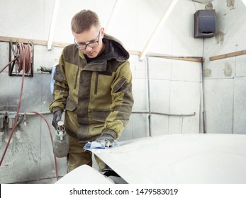 Cute Guy In Black Glasses With Black Gloves Displays The Shape Of The Hood For The Subsequent Painting Of The Car. Guy - A House Painter Working On A Car In The Garage