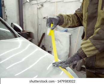 Cute Guy In Black Glasses With Black Gloves Displays The Shape Of The Hood For The Subsequent Painting Of The Car. Guy - A House Painter Working On A Car In The Garage