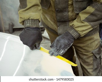 Cute Guy In Black Glasses With Black Gloves Displays The Shape Of The Hood For The Subsequent Painting Of The Car. Guy - A House Painter Working On A Car In The Garage