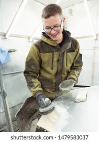 Cute Guy In Black Glasses With Black Gloves Displays The Shape Of The Hood For The Subsequent Painting Of The Car. Guy - A House Painter Working On A Car In The Garage