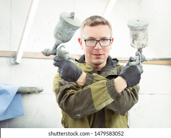 Cute Guy In Black Glasses With Black Gloves Displays The Shape Of The Hood For The Subsequent Painting Of The Car. Guy - A House Painter Working On A Car In The Garage