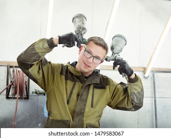 Cute Guy In Black Glasses With Black Gloves Displays The Shape Of The Hood For The Subsequent Painting Of The Car. Guy - A House Painter Working On A Car In The Garage