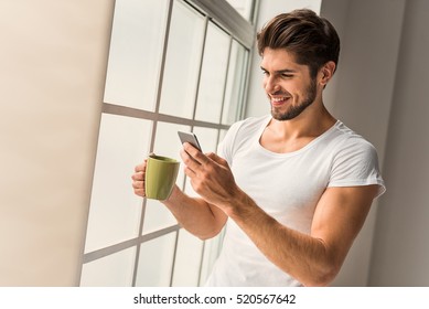 Cute Guy Using Mobile Phone At Home