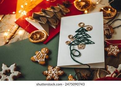 Cute handmade postcard with fir tree embroidering with green threads on wooden background. Homemade gingerbread cookies. Holiday craft, family tradition, quality time, simple easy do it yourself decor - Powered by Shutterstock