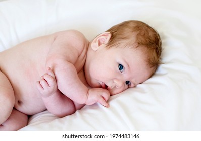 Cute Happy 3 Month Baby Boy Or Girl Lying On A White Sheet. Newborn Care, Colic, Teething Pain