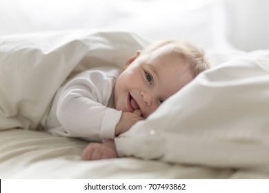 Cute happy 7 month baby girl in diaper lying and playing - Shutterstock ID 707493862