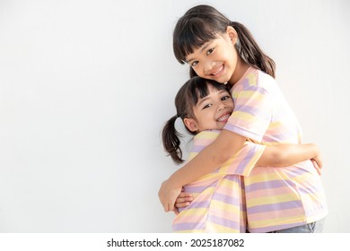 Cute happy Asian siblings hugging cuddling feeling love and connection, smiling kid girl sister embracing little girl sister on white background, 2 children good relationships - Shutterstock ID 2025187082