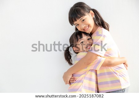 Cute happy Asian siblings hugging cuddling feeling love and connection, smiling kid girl sister embracing little girl sister on white background, 2 children good relationships