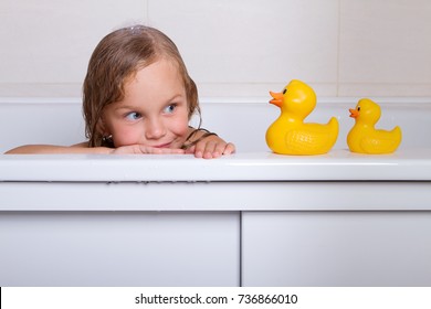Cute happy baby girl taking bath with foam and toys, child's hygiene, healthy lifestyle, carefree childhood concept