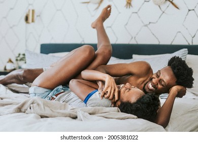 Cute happy black couple playing in bed - Shutterstock ID 2005381022