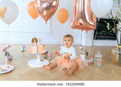 Cute Happy Blonde Baby Girl In Peach Tutu Sitting On Festiv Background. Birthday Party. Holiday Butter Iced Cake. Kid Holding Dirty Sticky Hands From Messy Cake. Smash Cake. Funny Toddler Eating Cake