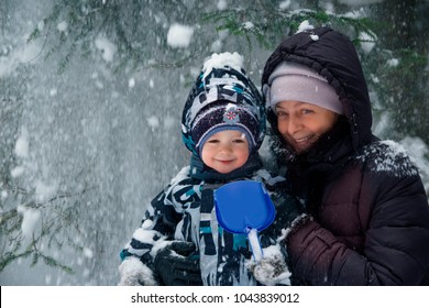 Cute and happy boy with grandmother in the snow forest