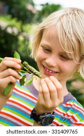 Cute, Happy Child In Nature Looking At A Caterpillar
