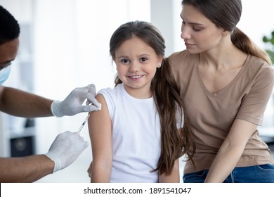 Cute Happy Girl Visiting Doctor With Her Mom, Getting Injection Of Covid-19 Vaccine At Hospital. Parent And Child Receiving Immunization Against Coronavirus At Clinic. Protection Against Viral Disease