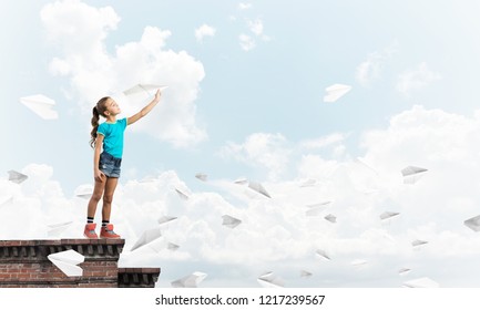 Cute Happy Kid Girl On Building Top Playing With Paper Plane