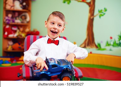 cute happy kid on wheelchair with present in kindergarten for kids with special needs