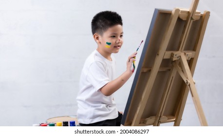 Cute Happy Little Asian Boy Painting With Water Color On Canvas Standing In White Room At Home, Creative Young Artist At Work. Kids Paint. Children Draw.