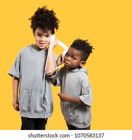 Cute And Happy Little Boys Sharing Headphones To Listen To Music On A Yellow Background