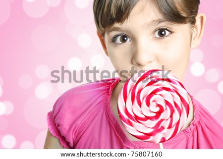 Cute happy little girl with lollipop candy in front of colorful pink background with copyspace
