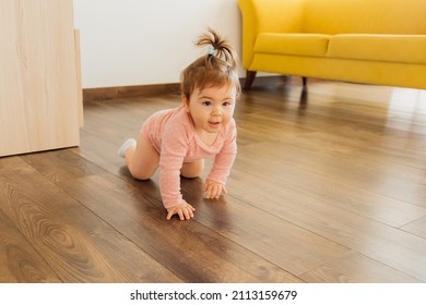 Cute Happy Little Toddler Baby Boy Is Crawling On A Wooden Floor At Home. Baby Crawls Toward The Camera In Slow Motion Smiling And Laughing In Living Room