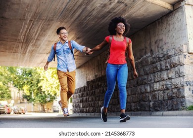 Cute Happy Multicultural Couple Running On The Street.