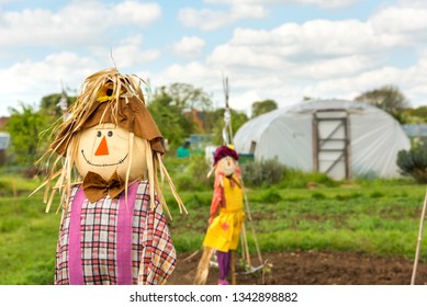 Cute happy straw filled boy scarecrow on allotments, made to guard the crops. A girl scarecrow is at the background. - Powered by Shutterstock