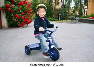 Cute Happy Toddler Wearing Helmet Riding Tricycle