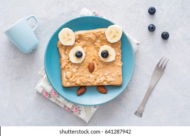 Cute, Healthy And Funny Breakfast For Kids: Peanut Butter Toast With Banana And Blueberries Shaped As Owl. Top View