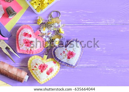 Cute hearts keychain with flowers beads. Hand felt and fabric keychain on bag or backpack. Summer accessorize for women or girls. Crafts concept. Wooden background with copy space for text. Top view